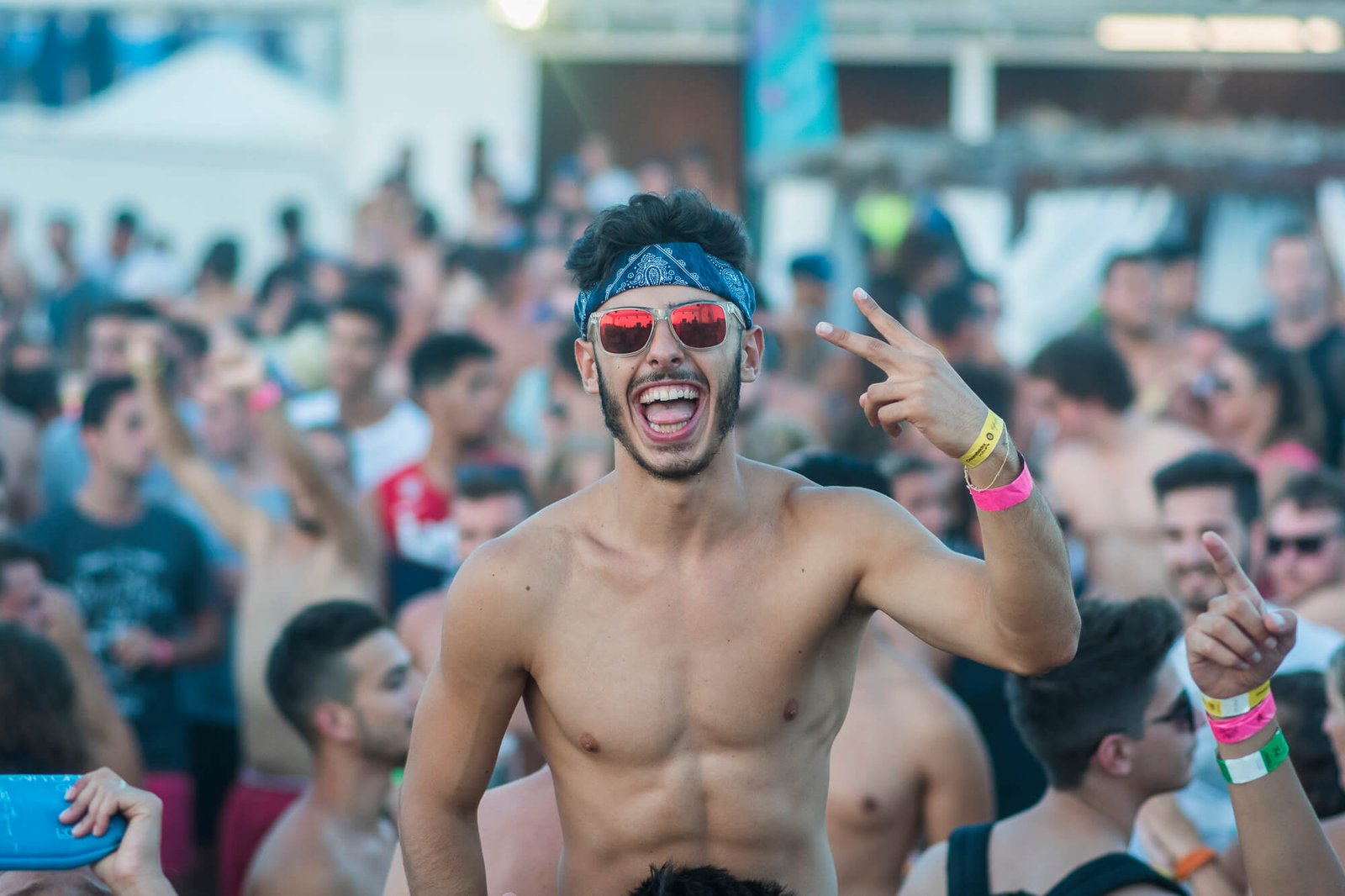Juicy Event beach party - participant souriant et levant la main tout en étant porté sur les épaules de son ami à la soirée plage animée
